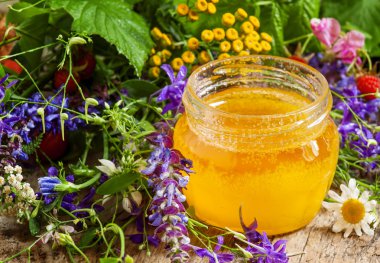 Bal ve ahşap bir masa üzerinde otlar