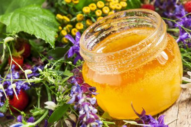 Bal ve ahşap bir masa üzerinde otlar