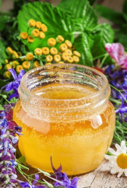 Bal ve ahşap bir masa üzerinde otlar