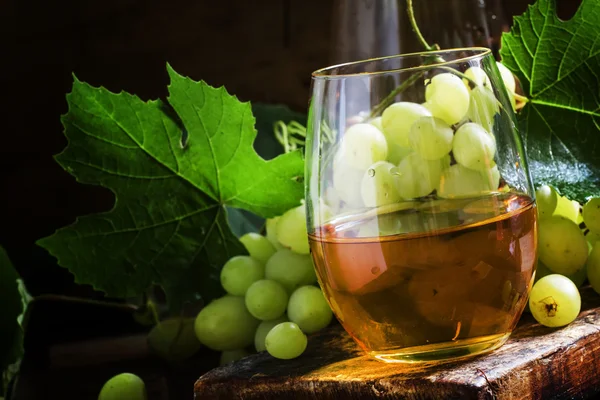 Vino blanco en copa, uvas verdes con hojas en bodega —  Fotos de Stock