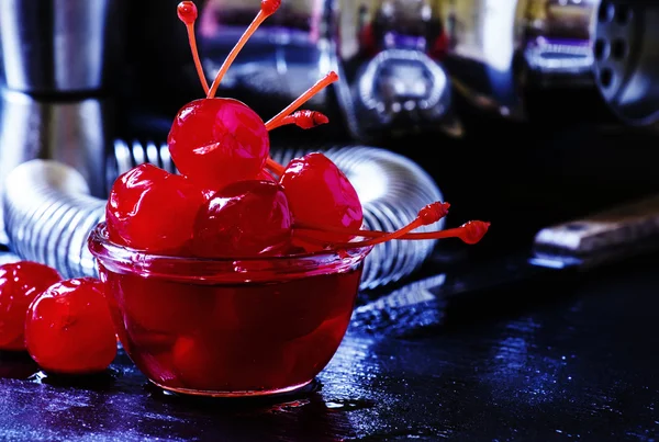 Ciliegie da cocktail rosse, strumenti da bar su sfondo scuro — Foto Stock
