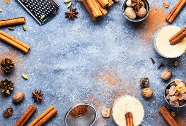 Eggnog sıcak kışı ya da sonbahar kokteyli sütlü, yumurtalı ve koyu romlu, tarçınlı ve hindistan cevizli, gri arka planda cam bardaklarda, Noel sofrasında, en üstte