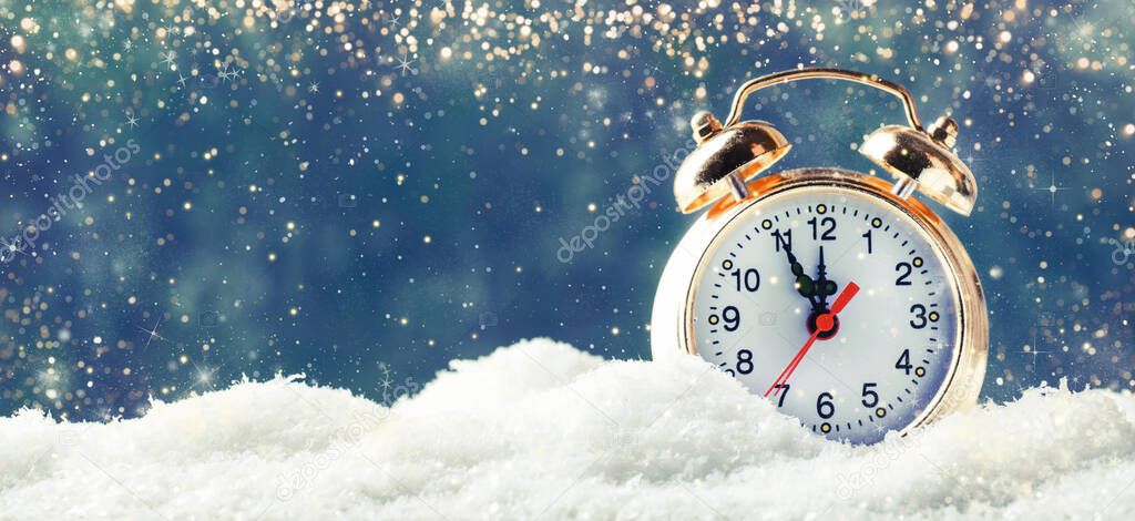 Christmas or New Year background with Golden alarm clock in snowdrifts on blue background with holiday lights counting last moments before Christmass Countdown to midnight. 