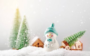 Mutlu Noeller ve fotokopi alanı ile mutlu yeni yıl kompozisyonu. Küçük kardan adam Noel ağacını peri ormanından eve taşıyor. Kış festivali arka planı