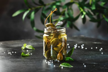 Terbiye edilmiş ya da turşulu kapari turşusu meyveleri kavanoza koyup gri mutfak masasında fotokopi alanı ile kapatıyorlar.