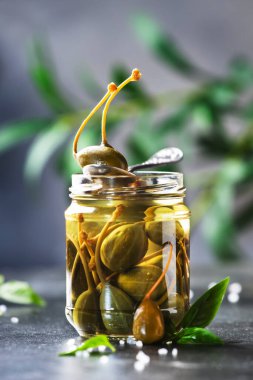 Terbiye edilmiş ya da turşulu kapari turşusu meyveleri kavanoza koyup gri mutfak masasında fotokopi alanı ile kapatıyorlar.