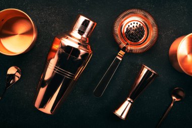Kokteyl yapmak için bakır bar aletleri ve barmen aksesuarları. Titretici, jigger, süzgeç, kaşık. Alkol içecekleri ve içecekler için hazırlık. Siyah arkaplan, üst görünüm