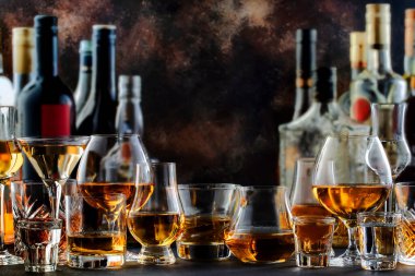 Sert alkollü içecekler ve bardaklarda damıtılıyor ve çeşitli şişelerde damıtılıyor: votka, konyak, tekila, viski, brendi ve viski, grappa, likör, vermut, tentür, rom. Kahverengi arkaplan