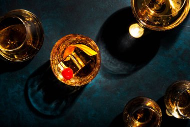 Viski, kiraz ve portakal kabuğu garnitürlü eski moda kokteyl, mavi masa, fotokopi alanı, üst manzara.