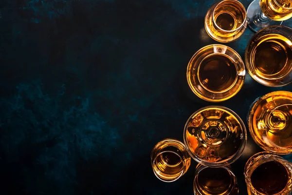 Sert alkollü içecekler, bardaklarda alkol ve damıtma: votka, konyak, tekila, viski, brendi ve viski, grappa, vermut, rom. Mavi arkaplan, üst görünüm