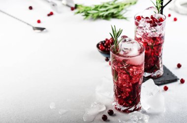 Buzlu yabanmersini kokteyli, buzlu biberiye ve meyveli viski bardağı, gri arka plan, kopyalama alanı