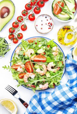 Domatesli taze karides salatası, marul, roka, avokado, salatalık ve beyaz arka planda limon sosu. Sağlıklı beslenme, temiz yemek konsepti. Üst görünüm 