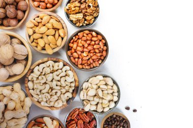 Fındık çeşitleri kaselerde. Fındık, fındık, fındık, fıstık, fıstık, çam fıstığı, yer fıstığı, macadamia, badem, Brezilya fındığı. Beyaz arkaplanda yiyecek karışımı, üst görünüm, kopyalama alanı