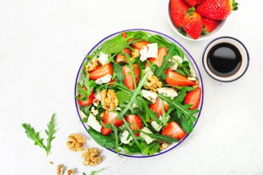 Yaz Çilek Salatası. Ispanak yaprakları, roka, ceviz, gri arka planda mavi peynir. Sağlıklı gıda konsepti. Düz yatış, üst görünüm
