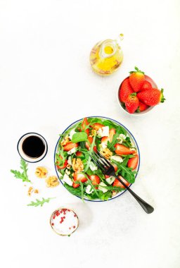 Yaz Çilek Salatası. Ispanak yaprakları, roka, ceviz, gri arka planda mavi peynir. Sağlıklı gıda konsepti. Düz yatış, üst görünüm
