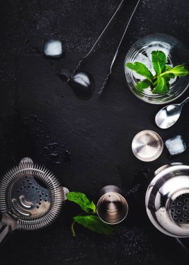 Kokteyl yapmak için çelik bar aletleri ve aksesuarlar. Titretici, jigger, süzgeç, kaşık, maşa, muddler. Alkol ve içecek hazırlama konsepti. Siyah arkaplan, üst görünüm, kopyalama alanı
