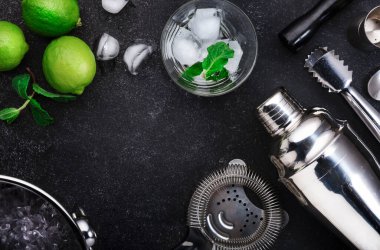 Bar aletleri. Limonlu mojito kokteyli, nane yaprağı ve buz. Soğuk içecek ve içecek hazırlığı. Siyah tablo, kopyalama alanı olan üst görünüm