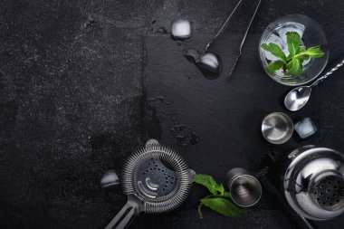 Kokteyl yapmak için çelik bar aletleri ve aksesuarlar. Titretici, jigger, süzgeç, kaşık, maşa, muddler. Alkol ve içecek hazırlama konsepti. Siyah arkaplan, üst görünüm, kopyalama alanı