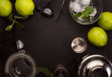 Bar aletleri. Limonlu mojito kokteyli, nane yaprağı ve buz. Soğuk içecek ve içecek hazırlığı. Siyah tablo, kopyalama alanı olan üst görünüm