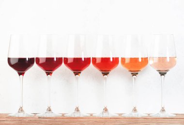 Rose wine glasses set on wine tasting. Different varieties, colors and shades of pink wines on white background clipart