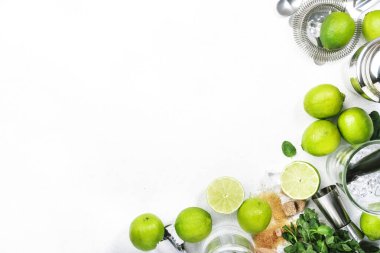 Mojito kokteyli hazırlama malzemeleri: kireç, nane, buz ve bar araçları, beyaz arkaplan, üst görünüm