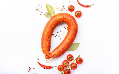 Beyaz mutfak masasında tütsülenmiş sosis çemberi baharatlar, domatesler ve sarımsak, doğal organik et ürünü, üst görünüm, kopyalama alanı