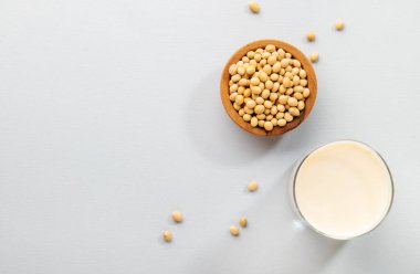 Gri masa arkasında vegan soya sütü ve fasulyesi. Sütsüz süt konsepti. Diyet içeceği. Sert ışık. Boşluğu kopyala