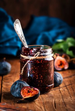 Kavanozda kırmızı incir reçeli ve taze mavi incir. Ev yapımı hazırlıklar ve konserveler. Kırsal ahşap masa arkaplanı