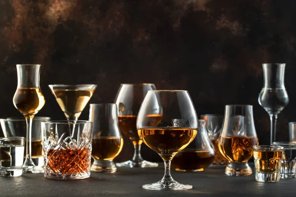 烈性酒 烈性酒和烈性酒 在各种杯子中蒸馏 伏特加酒 白兰地 苏格兰威士忌等 褐色吧台面背景 — 图库照片
