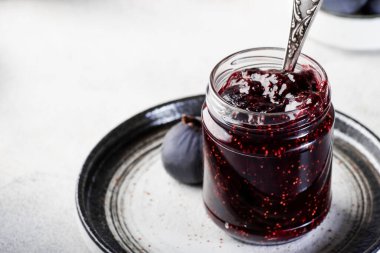 Tatlı kırmızı incir kavanozu. Taze mavi incirler. Ev yapımı hazırlıklar ve konserveler. Gri tablo arkaplanı, kopyala