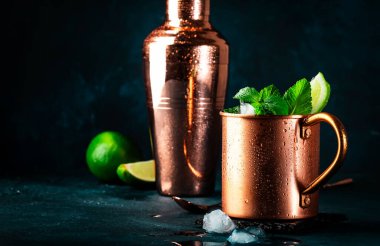 Bakır bardakta alkollü Moskova katırı kokteyli, limon, zencefilli bira, votka ve nane. Mavi masa, bakır çubuk araçları