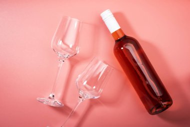 Pembe fırında şişeli gül şarabı kadehi. Rosado, rosato ya da kırmızı şarap tatma. Boşluğu kopyala, üst görünüm