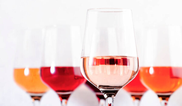 Rose wine glasses set on wine tasting. Different varieties, colors and shades of pink wines on white background