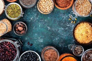 Çeşitli organik süper yiyecekler, fasulyeler, tahıllar, tahıllar, baklagiller, yeniden kullanılabilir kutular ve kavanozlardaki tohumlar. Üst görünümü kopyala. Mavi arkaplan