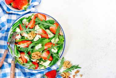 Ispanaklı çilek salatası, roka, ceviz, gri masada mavi peynir. Sağlıklı yiyecekler. Üst görünüm