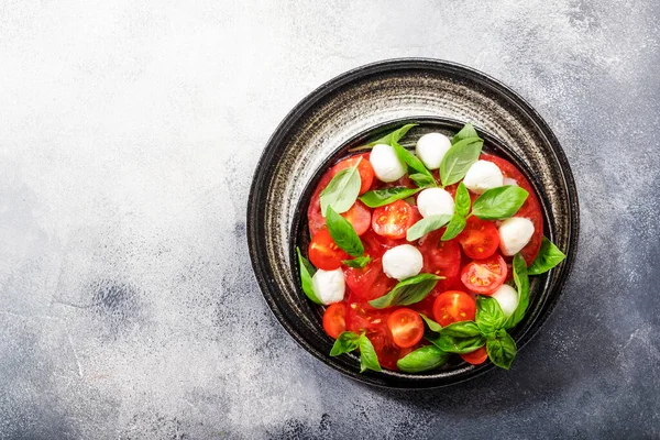 新鮮な緑のバジルの葉と赤トマトと白のモッツァレラチーズと夏のカプレーゼサラダ 灰色のテーブル トップ表示 — ストック写真