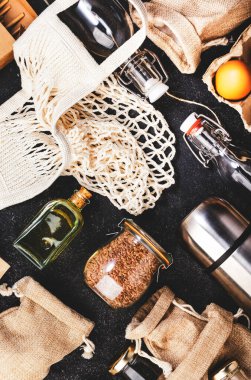 Geri dönüşümlü, yeniden kullanılabilir çevre dostu çantalar, paket, şişe, kutu ve konteynırlar, ağ torbası. Gri masa, üst manzara. Sıfır atık, plastiksiz ve sürdürülebilir yaşam konsepti