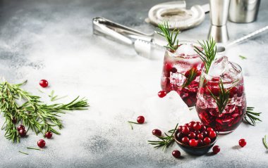 Kızılcık, votka, buzlu cin, biberiye ve bardakta böğürtlen. Yaz boyu içki. Gri tablo arkaplanı