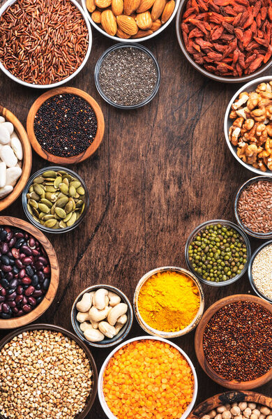 Поверхности, ножки, керали, орехи, семена в мисках на деревянном фоне. Superfood as chia, spirulina, beans, goji berries, quinoa, turmeric and other. Вид сверху