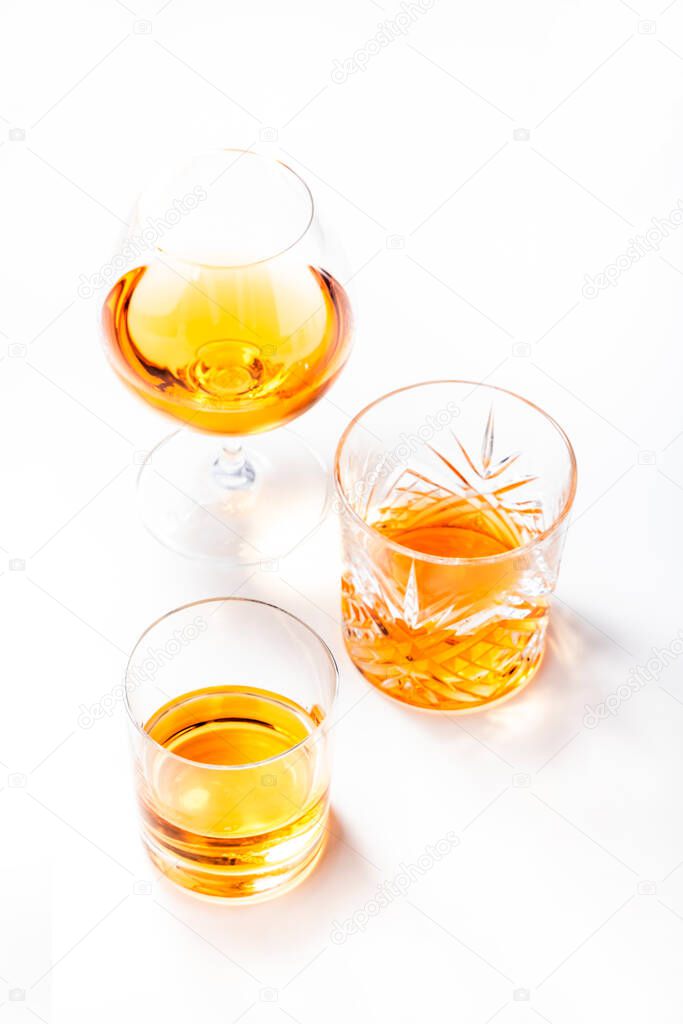 Strong alcoholic drinks, spirits and distillates in glasses: vodka, cognac, scotch, whiskey and other. White background. Hard light