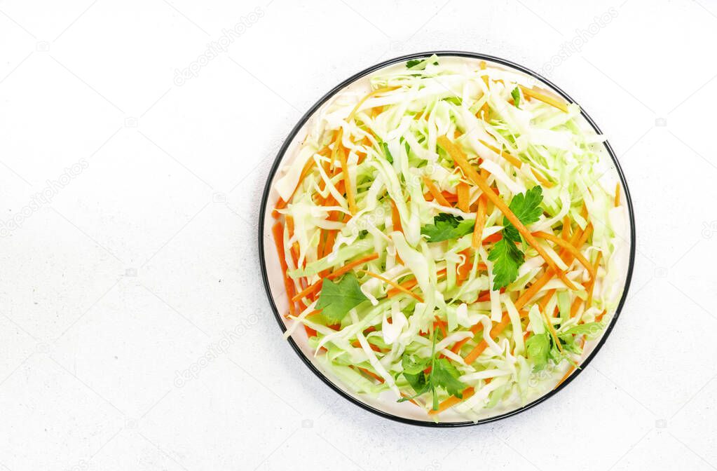 Salad coleslaw with cabbage, carrot on white kitchen table background. Top view, copy space