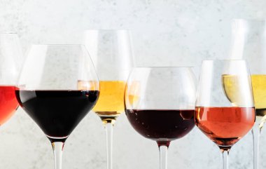 Şarap çeşitleri. Kırmızı, beyaz, şarap kadehlerinde gül şarabı ve gri arka planda şişeler. Şarap barı, dükkan, tatma konsepti.