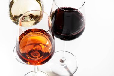 Beyaz arka planda kırmızı, gül ve beyaz şarap bardakları, üst manzara. Şarap barı, dükkan, şaraphane, şarap tatma konsepti. Sert ışık ve sert gölgeler