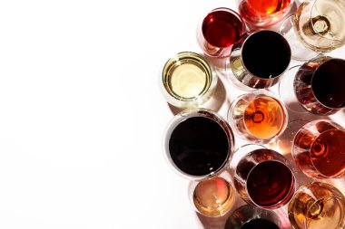 Beyaz arka planda kırmızı, gül ve beyaz şarap bardakları, üst manzara. Şarap barı, dükkan, şaraphane, şarap tatma konsepti. Sert ışık ve sert gölgeler