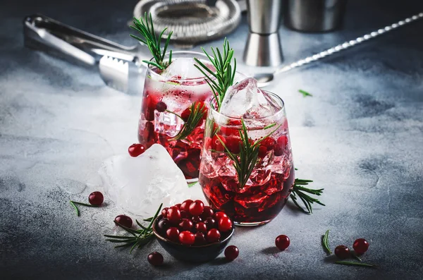 ウォッカ ジュース ローズマリー 赤い果実と冬のクランベリーカクテル お祭り騒ぎだ 負の空間を持つ灰色のテーブルの背景 — ストック写真
