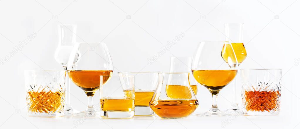 Strong alcohol drinks, hard liquors, spirits and distillates iset in glasses: cognac, scotch, whiskey and other. White background