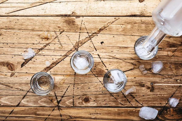 俄罗斯伏特加酒在木制桌子上的玻璃杯里 冰镇烈酒在迷雾的杯子里 顶视图 负空间 — 图库照片