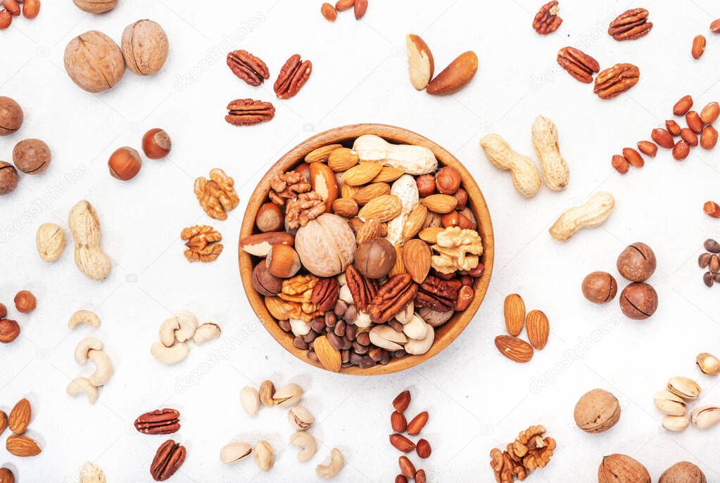 Nut mix in bowl. Almonds, hazelnuts, walnuts and other. Healthy food snack mix on white table, top view, copy space