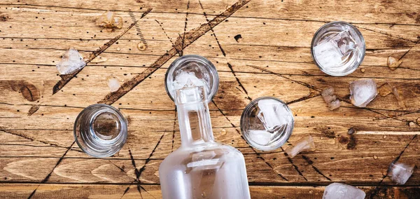 俄罗斯伏特加酒在木制桌子上的玻璃杯里 冰镇烈酒在迷雾的杯子里 顶视图 负空间 — 图库照片