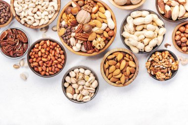 Fındıklar kaselerde. Badem, fındık, ceviz ve diğerleri. Sağlıklı yiyecek karışımı beyaz masa, üst görünüm, kopyalama alanı